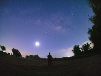 Man standing on field against sky at night