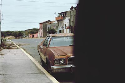Car on street by buildings against sky