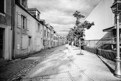 Empty road amidst buildings against sky