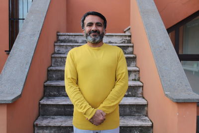 Portrait of smiling man standing on staircase against building