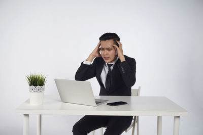 Young man using mobile phone while sitting on table