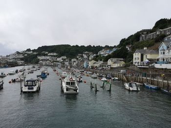 Sailboats moored on sea by town against sky