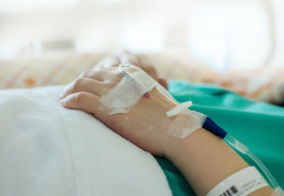 Close-up of human hand on bed