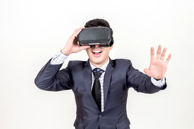 Young businessman using virtual reality simulator against white background