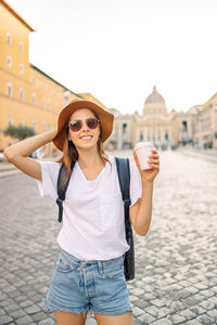 Portrait of young woman standing against buildings