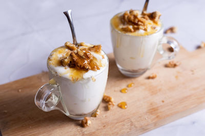 Cups of yogurt with honey and nuts on white background