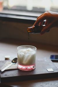 Close-up of hand holding drink on table