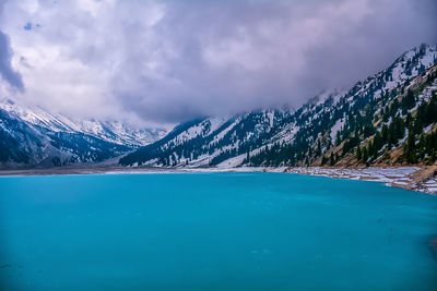 Scenic view of lake by mountains against sky