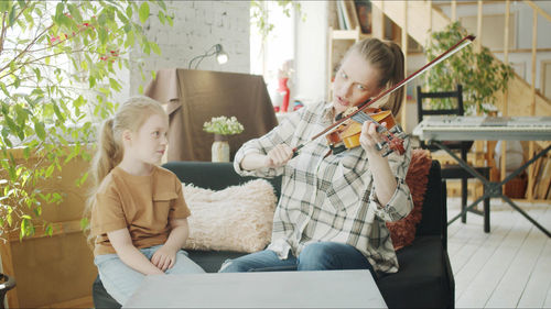 Teacher teaching violin to student at home