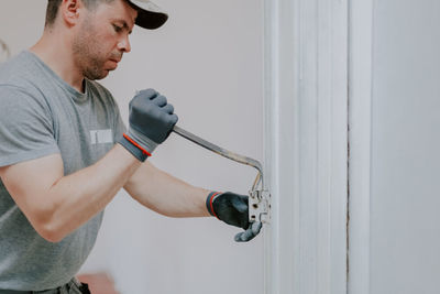 Hands of a man working with a crowbar indoors.