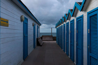 Empty footpath amidst buildings against sky