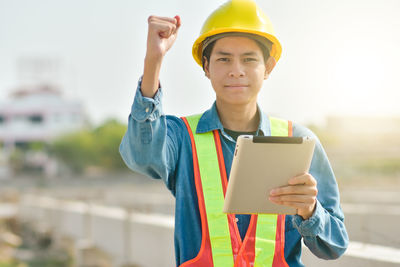 Portrait of mid adult man using mobile phone while standing at construction site