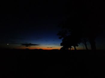 Silhouette trees on landscape against sky at sunset