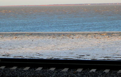 Close-up of railroad track by sea against sky