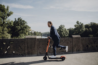 Businessman with e-scooter on a bridge