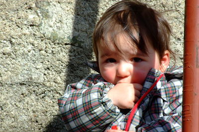 Close-up portrait of cute baby boy against wall