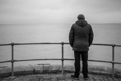 Rear view of man looking at sea against sky