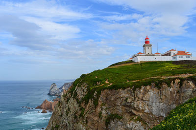 Lighthouse by sea against sky