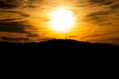 Silhouette landscape against orange sky