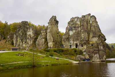 Rock formations by lake against sky