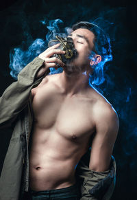 Young man with gas mask against black background