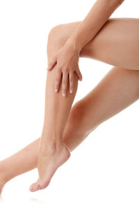 Low section of woman touching hand over white background