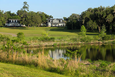 Scenic view of lake by house and trees