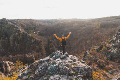 Rear view of man standing on rock against mountain