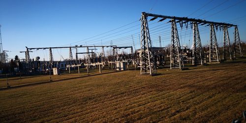 Low angle view of electricity pylon on land against clear sky