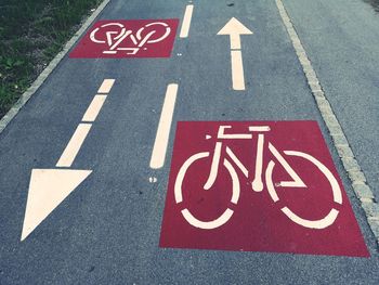 High angle view of arrow symbols with bicycle lane sign on road in city