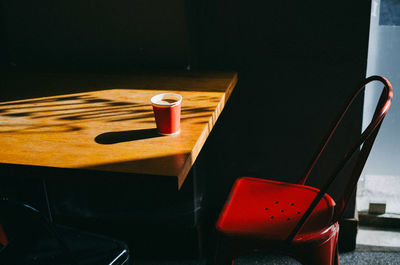 High angle view of coffee cup on table by chair in cafe