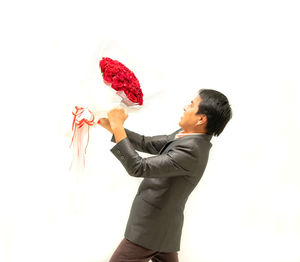 Woman holding red flowers against white background