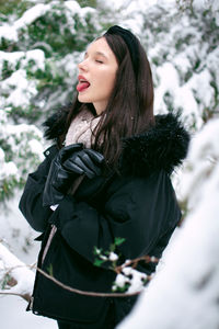 Portrait of young woman standing against trees