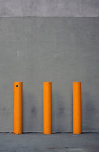 Yellow bollards against concrete wall