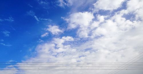 Low angle view of power lines against blue sky