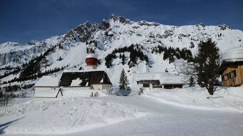 Snow covered house and mountains against sky