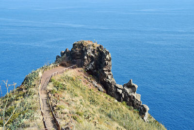 High angle view of rocks by sea against blue sky