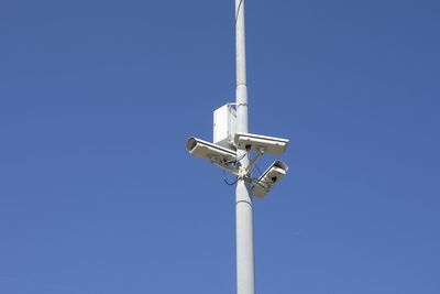 Low angle view of security camera on pole against sky