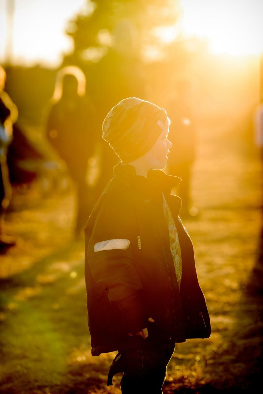 lifestyles, leisure activity, holding, focus on foreground, rear view, standing, person, waist up, men, three quarter length, headshot, casual clothing, lens flare, photography themes, sunset, unrecognizable person, outdoors