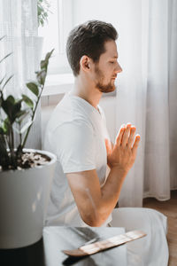 Side view of man meditating while sitting at home