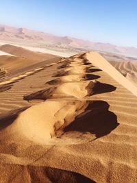 Sand dunes in desert against clear sky