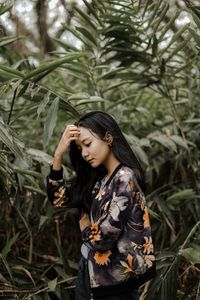 Young woman standing against plants in park