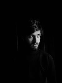 Portrait of young man against black background