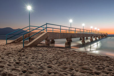 Footbridge over sea against clear sky during sunset