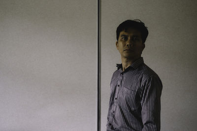 Side view portrait of mid adult man standing by wall