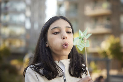 Girl blowing on pinwheel outdoors