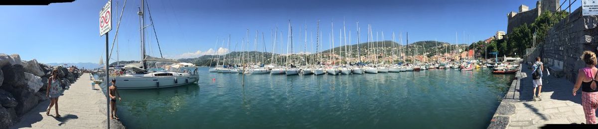 Sailboats moored in harbor against sky