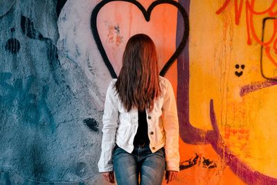 Full length of woman standing against graffiti wall