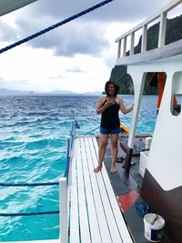 Full length of woman standing on railing against sea