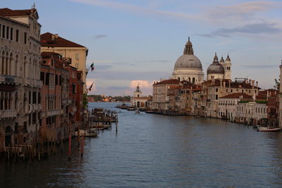 Buildings by river against sky